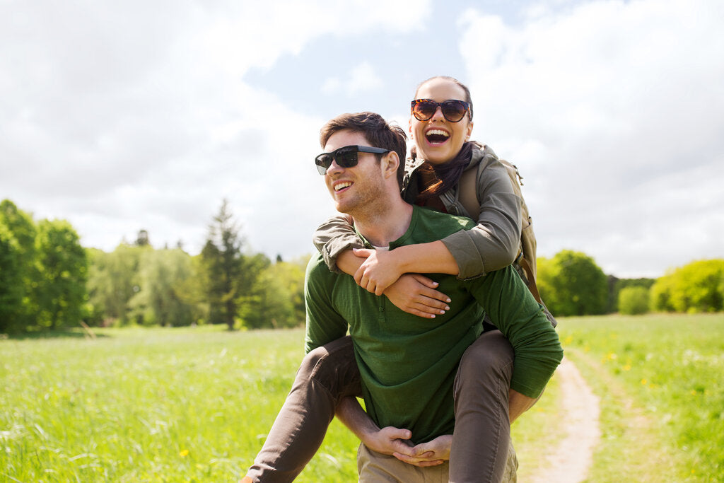 Couple enjoying a sunny hike while wearing long sleeves and sunglasses, highlighting the importance of UPF clothing and sun protection during outdoor activities.