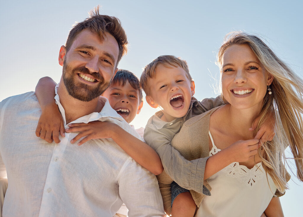 Smiling family enjoying a sunny day in Florida, highlighting the importance of sun protection with sunscreen and UPF-rated clothing for safe, carefree outdoor fun.