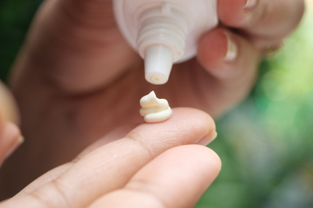Close-up of sunscreen being dispensed onto a fingertip, emphasizing the importance of applying the right amount for effective sun protection.