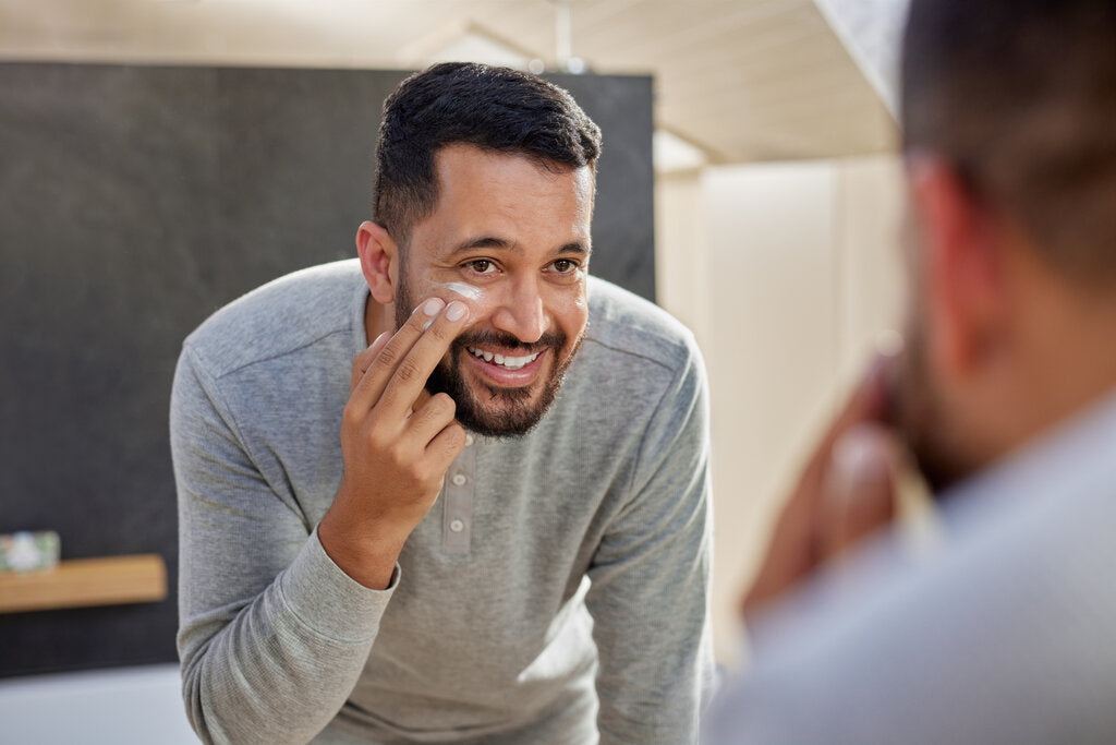 Man applying sunscreen while wearing a UPF 50+ Henley shirt, highlighting the ease and importance of daily sun protection.