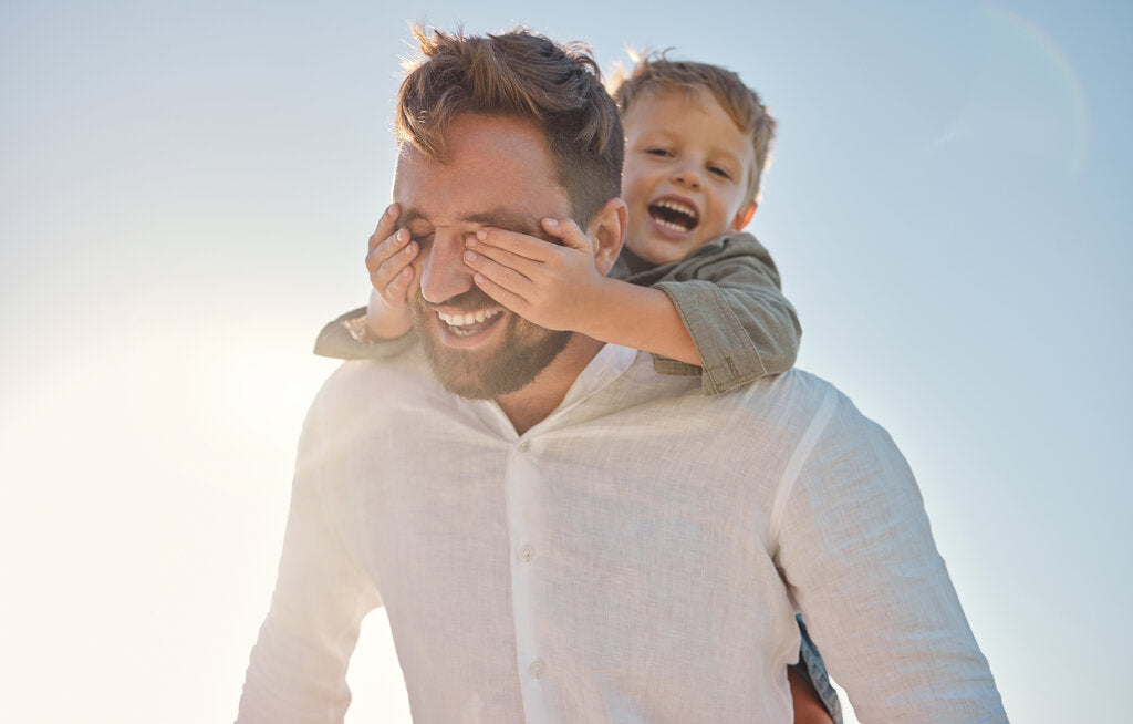 Father and son enjoying a sunny day outside, illustrating the need for UV protection through daily habits like wearing UPF clothing and using sunscreen.